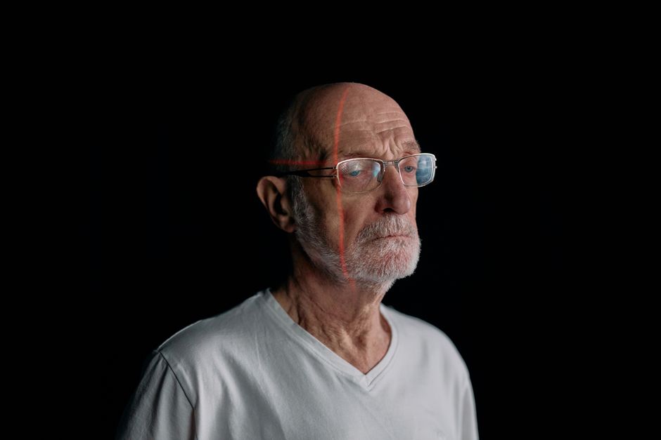 Elderly man with facial recognition lines on a black background. Studio shot.