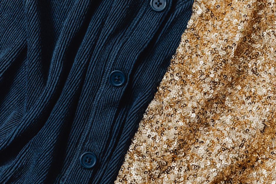 A detailed close-up of dark blue knitwear with buttons and gold sequin fabric, showcasing texture contrast.