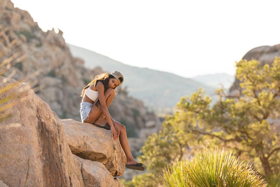 Woman sitting on rock in summer, enjoying scenic mountain view. Perfect for travel and lifestyle themes.