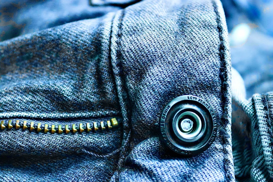 Detailed close-up of denim fabric highlighting a button and zipper, showcasing texture and design.