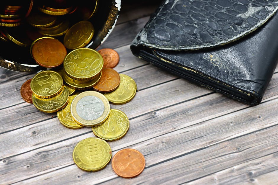 A worn-out leather wallet and scattered euro coins on wooden surface suggest economic hardship.