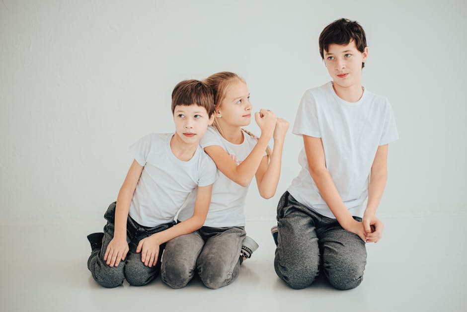 Caucasian siblings posing playfully in a studio with white background.