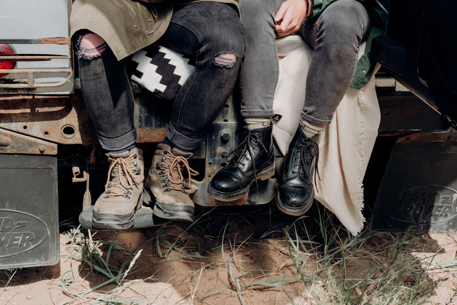 Two people sitting on a vehicle with rugged boots, ready for adventure in the outdoors.