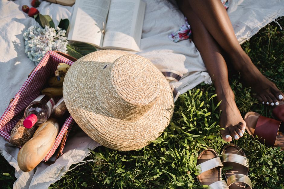 A relaxing summer picnic scene with a straw hat and open book on a blanket.
