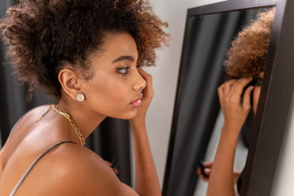 Close-up of a woman applying makeup while reflecting in a mirror indoors.