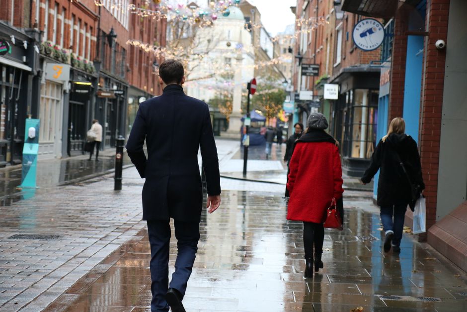 People walking in the rain at London's Seven Dials, capturing a typical bustling street scene in winter.