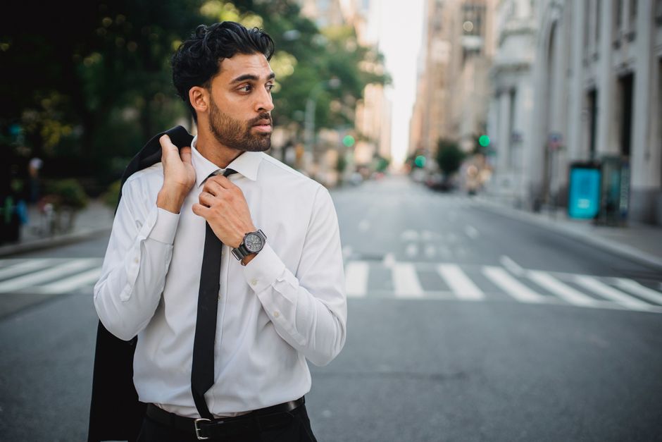 Confident businessman in formal attire standing on a quiet city street.