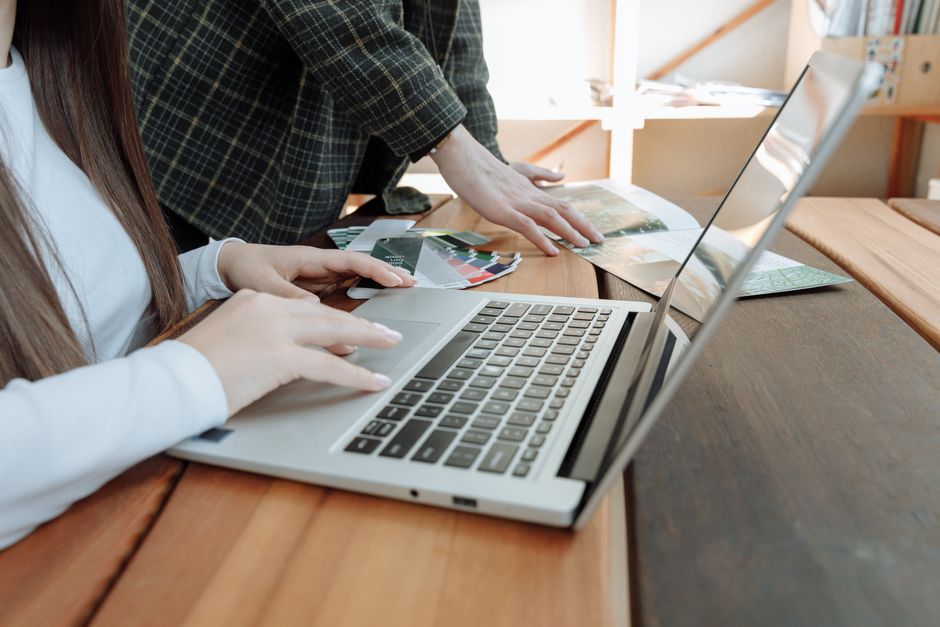 Close-up shot of hands working collaboratively on a laptop at a startup office, focused on teamwork.
