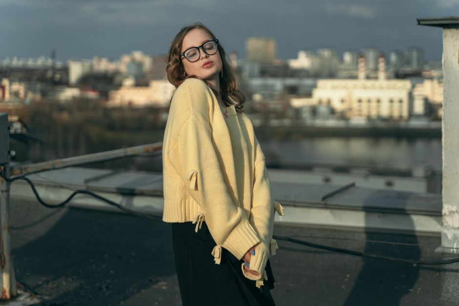 Young woman in cozy sweater on a rooftop in Minsk enjoying the cityscape view.
