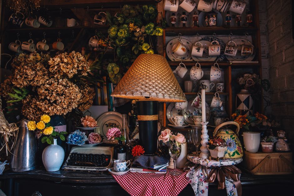 Charming vintage tea room with floral decor, antique typewriter, and tea sets creating a cozy atmosphere.