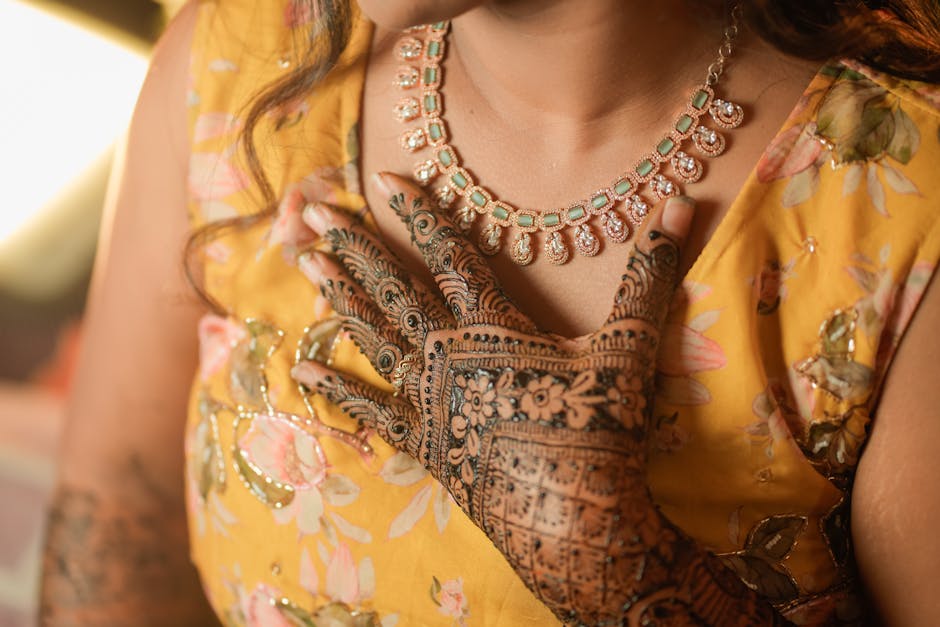 Intricate henna design complements a beautiful traditional necklace on a vibrant outfit.