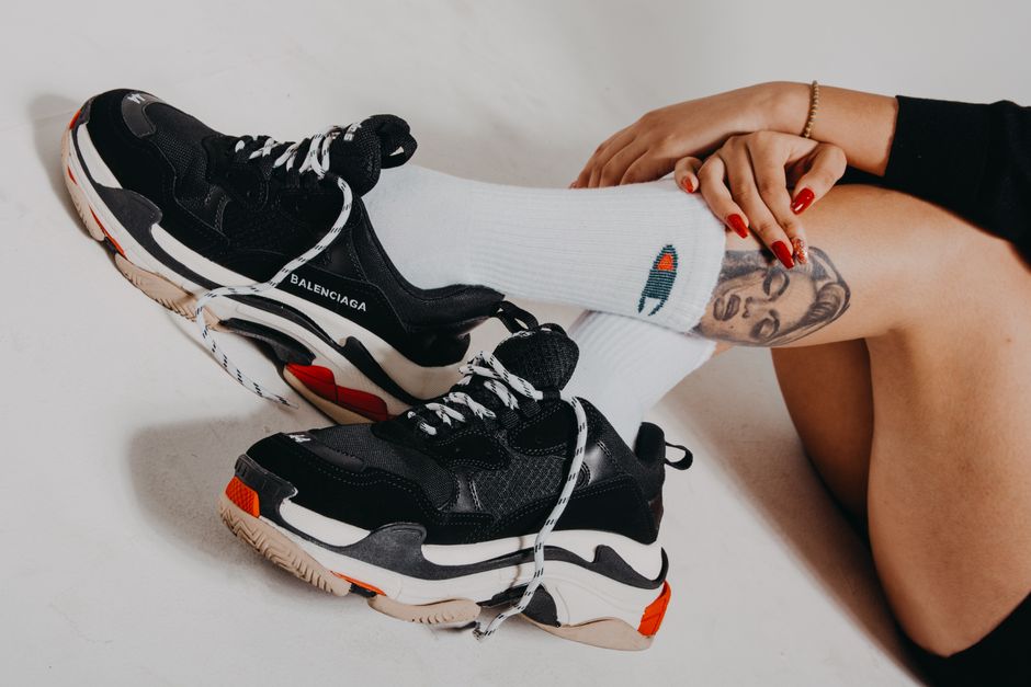 Close-up of Balenciaga sneakers and tattooed legs for a stylish fashion concept.