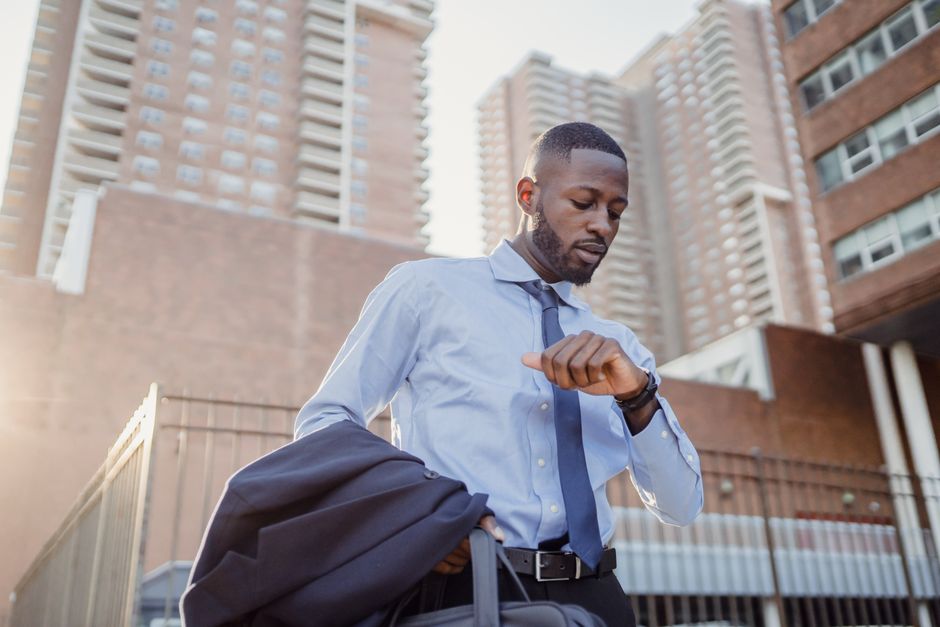 Young professional checking time while walking in a modern cityscape. Urban business lifestyle.