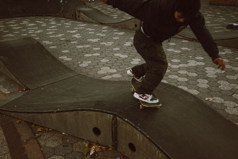 A skateboarder executes a trick on a curved ramp in an urban skatepark, showcasing skill and balance.