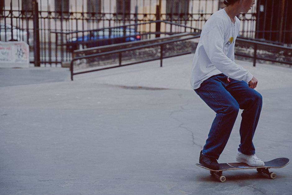A young man skateboards skillfully in an outdoor skatepark, showcasing balance and agility.