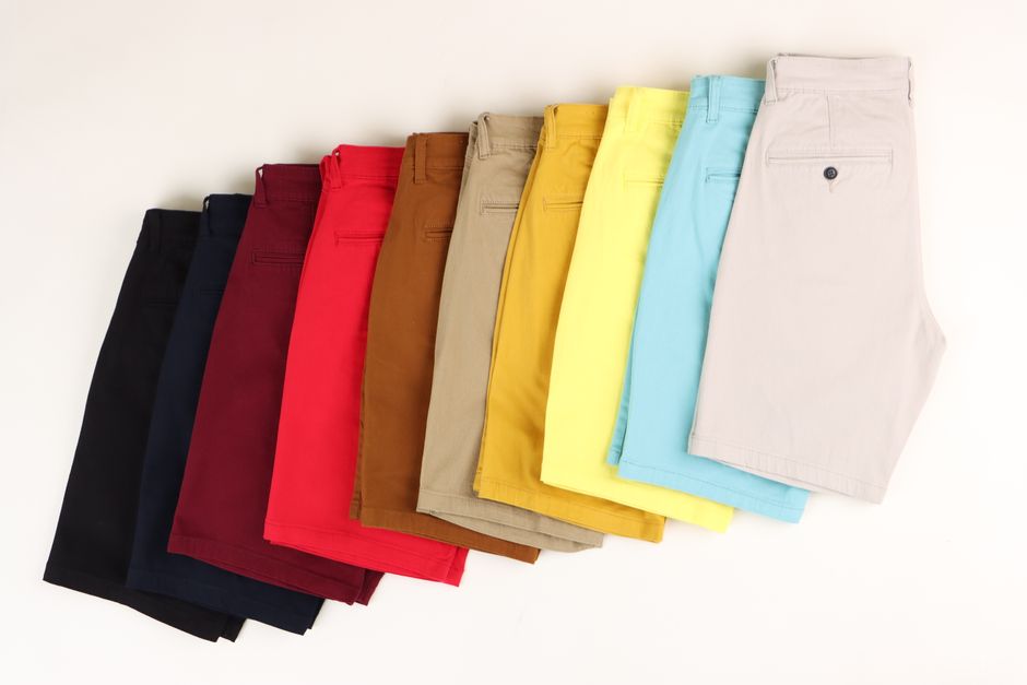 A variety of men's shorts arranged in a gradient of colors from black to light beige.