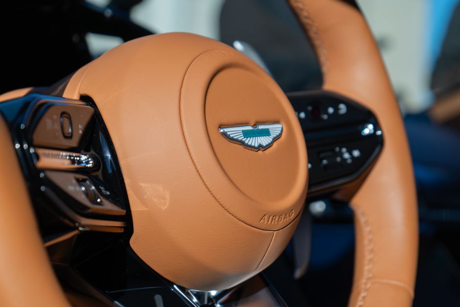 Close-up of a luxury car's leather steering wheel with logo.