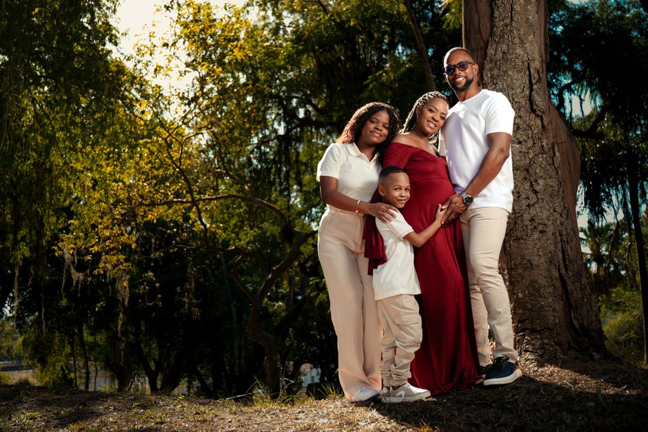 A happy family of four posing together outdoors, showcasing love and togetherness.