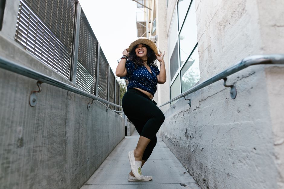 A woman in casual attire enjoys dancing outdoors in a lively urban alley.