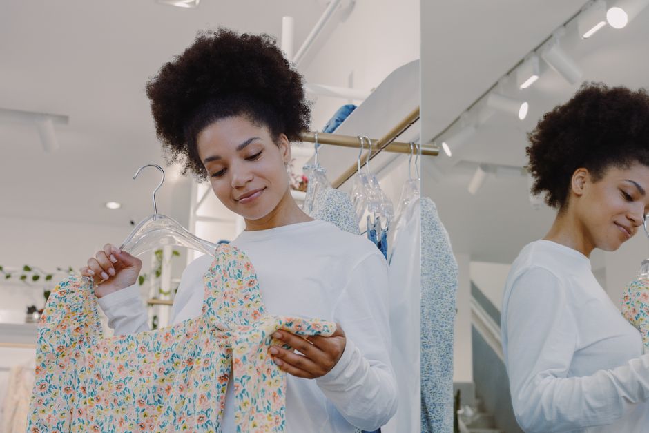Woman examines a floral top in a modern boutique, embracing casual shopping joy.