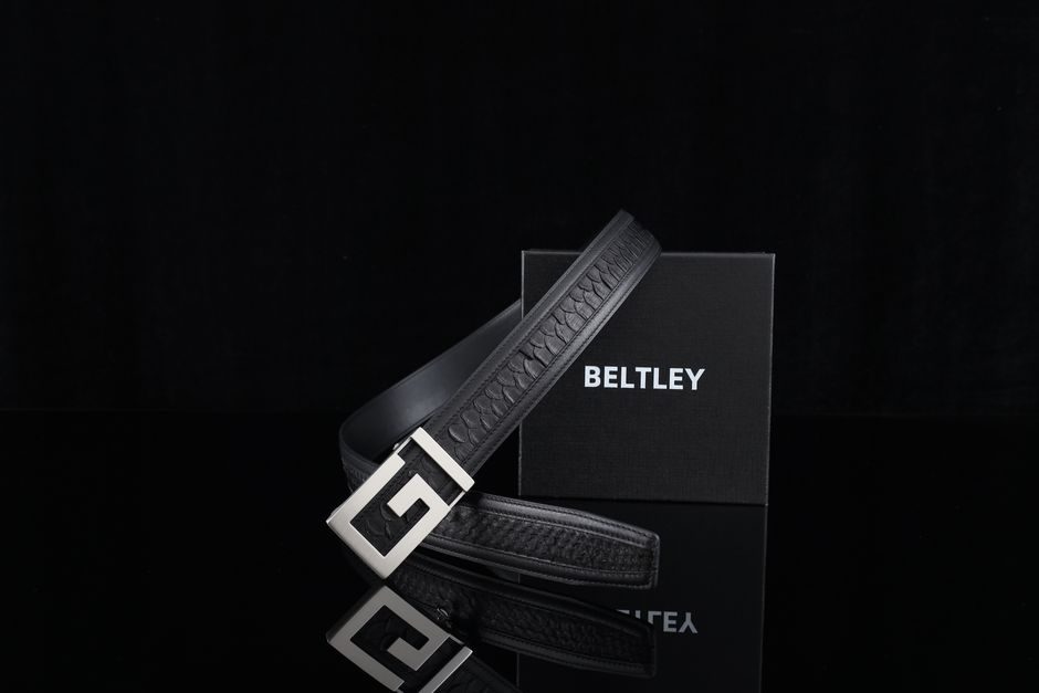 High-quality black leather belt set against a sleek elegant reflective surface with branded box.