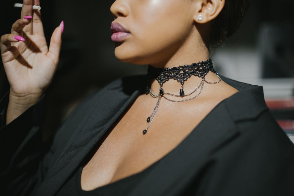Close-up of a stylish woman in a black top smoking a cigarette, showcasing jewelry.