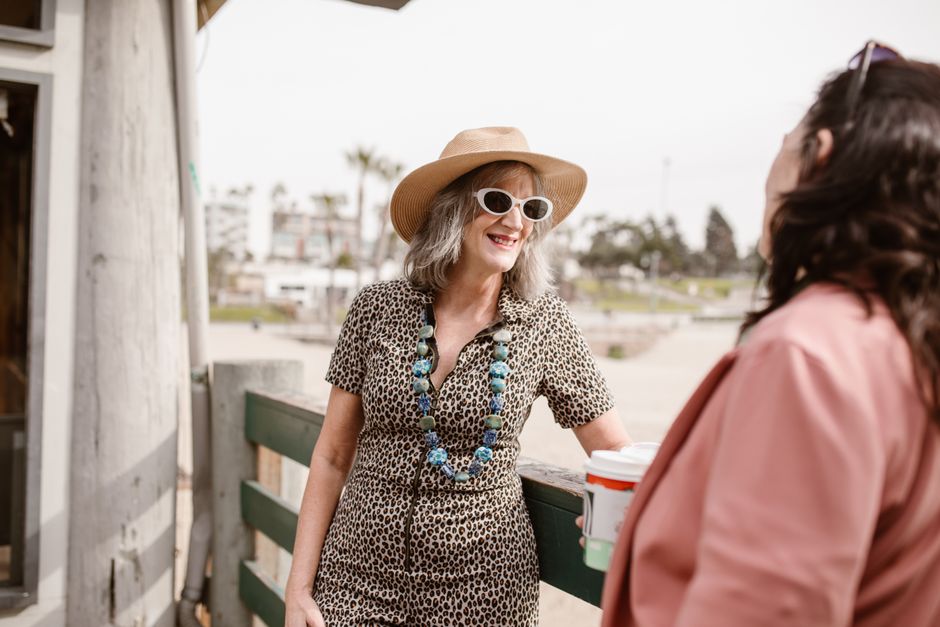 Two stylish women chatting outdoors, showcasing summer fashion and joy.
