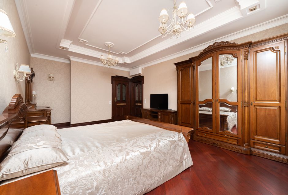 Luxurious bedroom with wooden furniture, chandeliers, and lavish bed linens creating a warm ambiance.