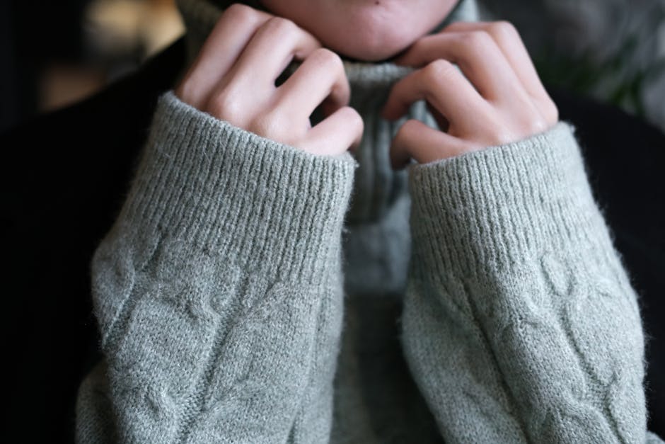 Warm and soft hands tucked into a knitted turtleneck sweater for a cozy winter feel.
