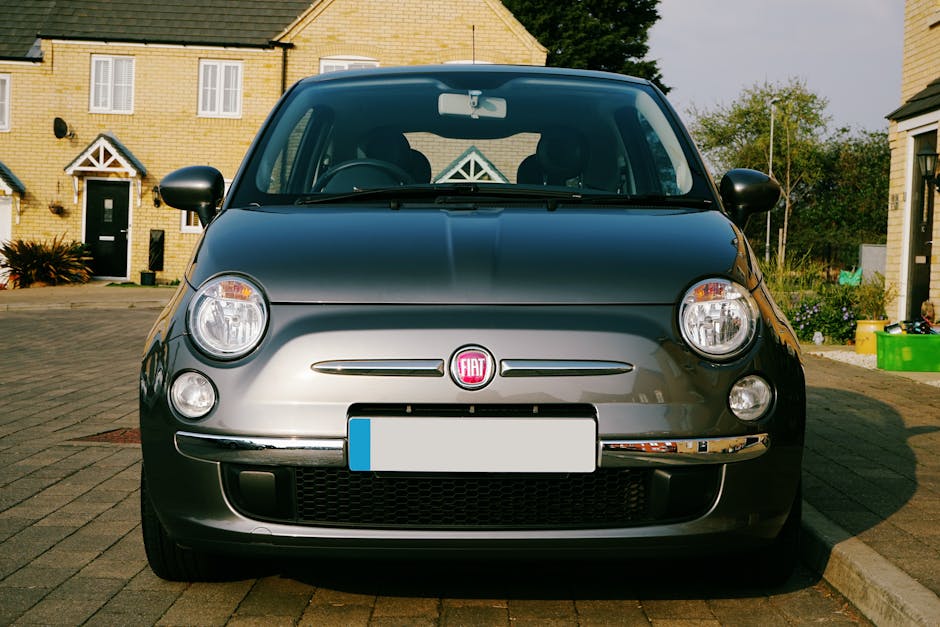 Classic Fiat 500 car parked on a residential street in the UK on a sunny day.