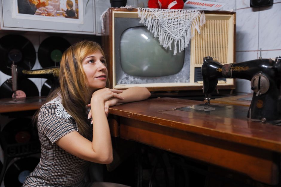 A nostalgic retro setup with woman beside vintage sewing machine and TV.