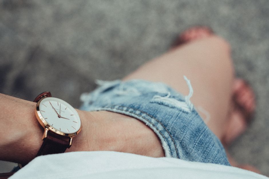 Close-up of a stylish wristwatch paired with denim shorts, evoking a casual summer vibe.