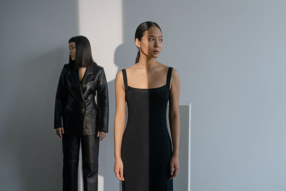Two stylish Asian women in a contemporary studio with dramatic lighting.