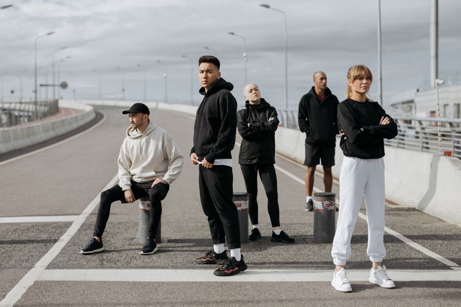 A diverse group of stylish adults posing in sportswear on an urban street.