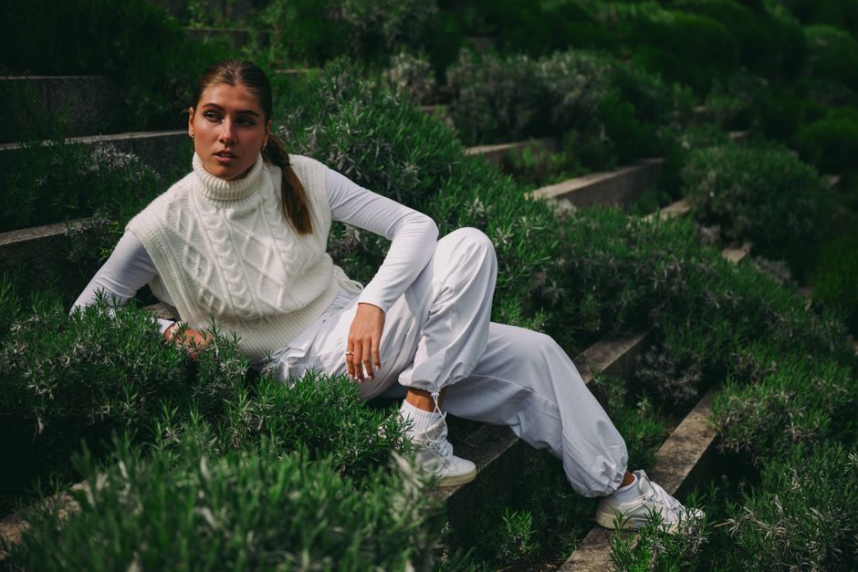 Woman in white attire posing on lush garden steps in Cologne, Germany.