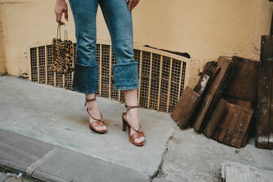 Stylish woman in jeans holding a leopard print bag on city street.