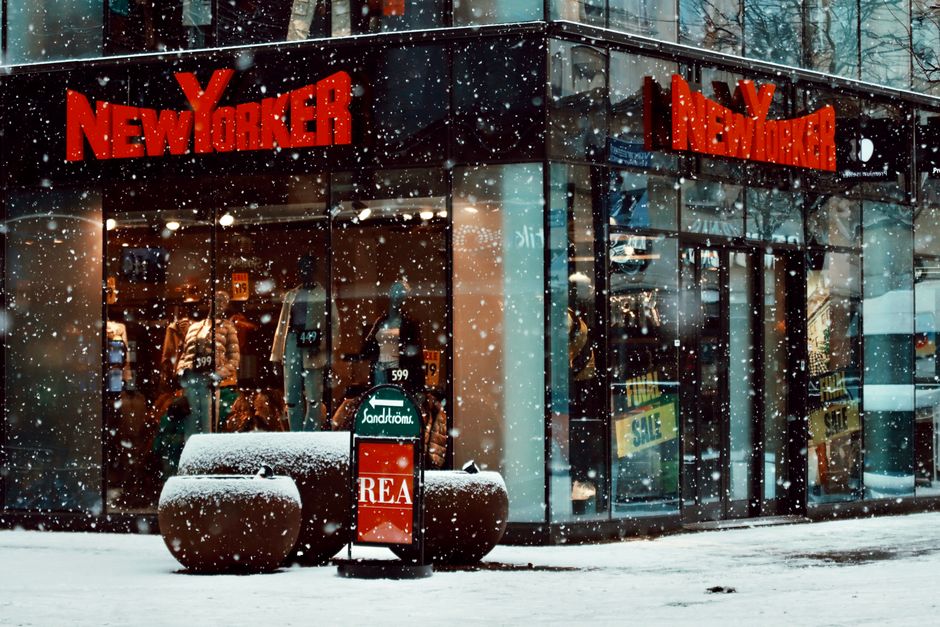 Snowfall at a bustling New Yorker store in Jönköping, Sweden, during winter.