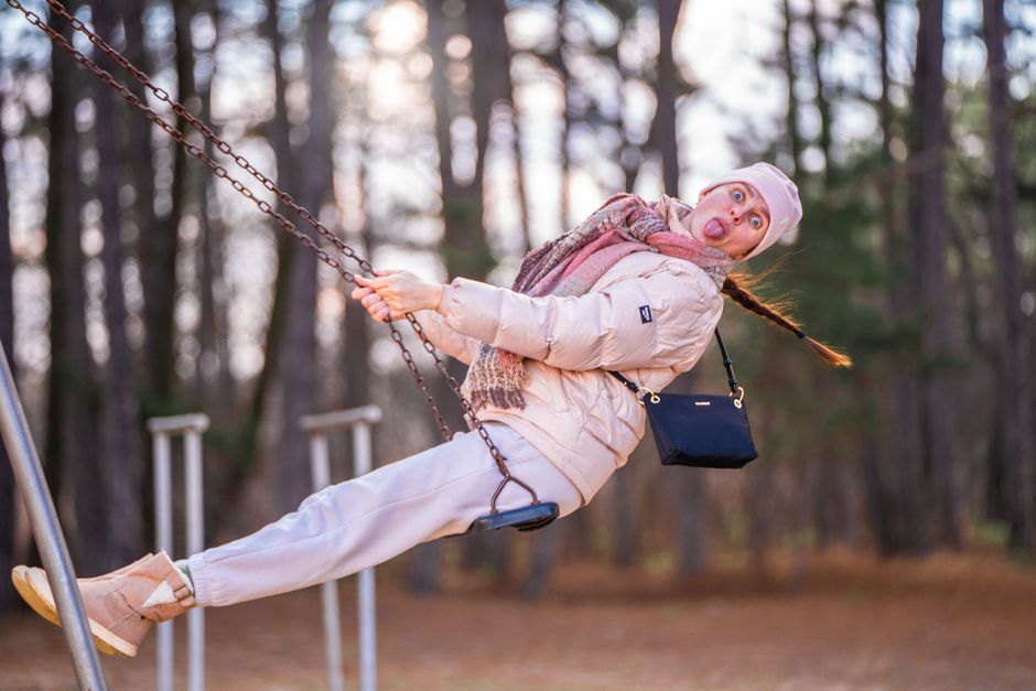Woman on swing outdoors in autumn forest, expressing joy and fun.