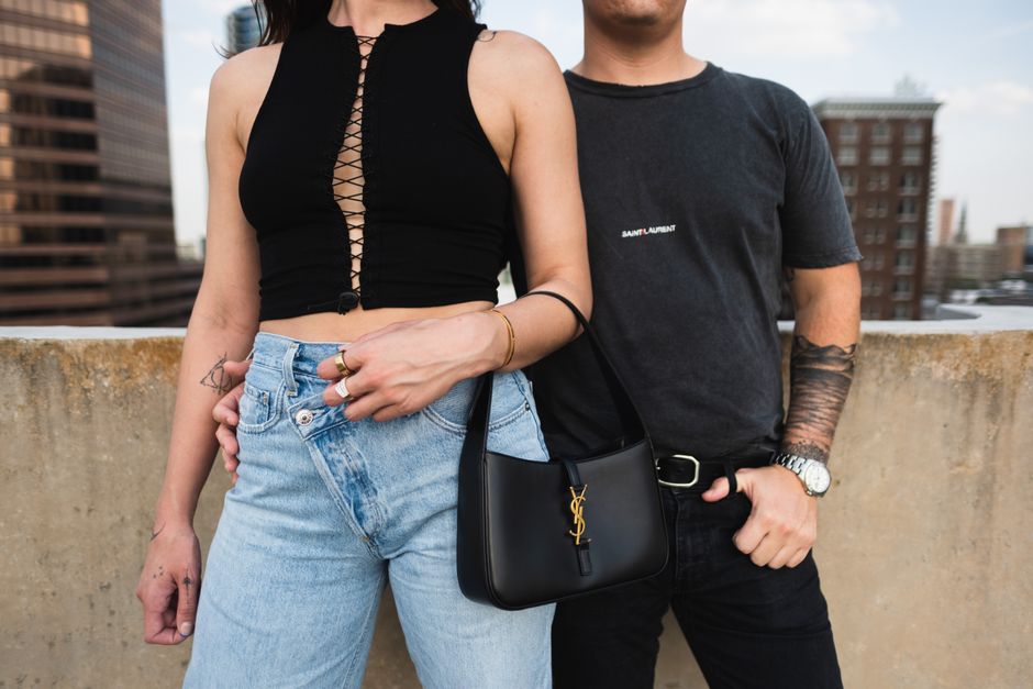 Stylish couple posing on a rooftop, showcasing urban fashion and accessories.